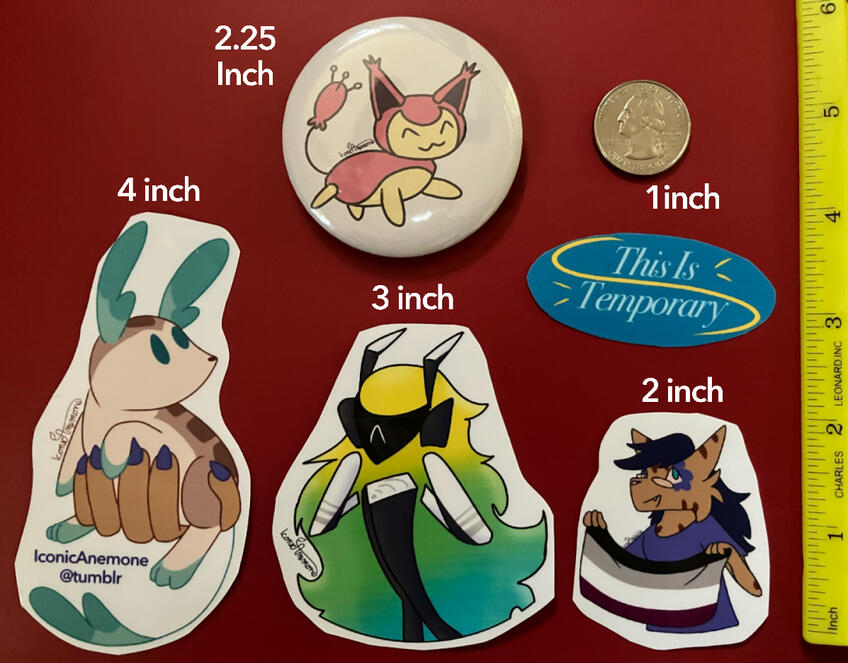 A photo of four stickers and one button next to a ruler and a quarter. They all have labels, showing their sizes, with the button being 2.25 inches, and the stickers scaling up to 1, 2, 3 and 4 inches